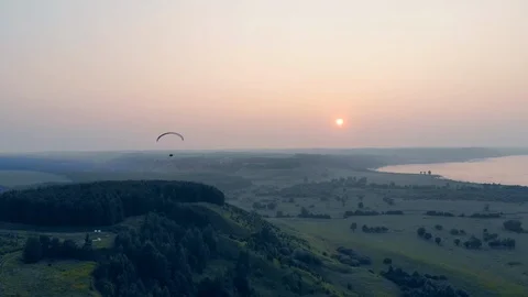 The sun is setting while the paraplane is floating in the sky. Parachute Stock Footage 114179130
