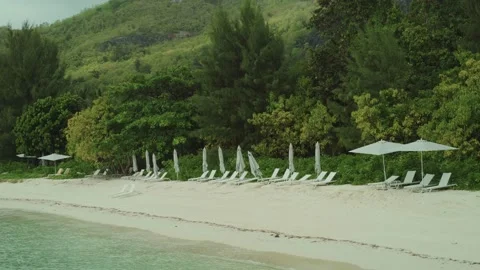Sun shade umbrellas and beach chairs on shore in luxury resort on island Stock Footage 197337451