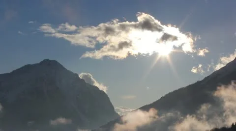 Sun shines from behind a cloud between two mountains Video stock 21650829