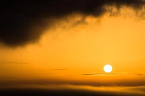The sun shines as a fireball between two cloud layers Stock Photos