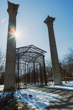 Sun shines on an open structure with columns in a snow-covered park on a cl.. Foto stock