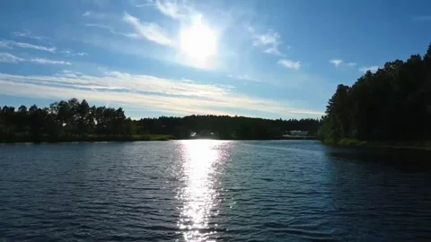 Sun shines over a river surrounded by trees in Norway during the daytime Stock Footage 340204948
