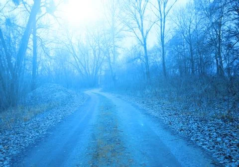 The sun shines over the road in a dark fairy Stock Photos