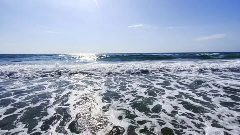 The sun shines on the seashore, a light breeze and waves touching the sand. Vídeos de archivo 313530741