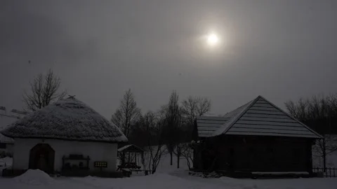 The Sun Shines Through Cloud Over Two Traditional Cossack Huts During A Snow Stock Footage 335322182