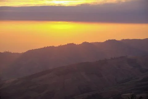 The sun shines through the clouds above the mountains. Stock Photos