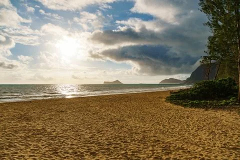 The sun shines through clouds on the beach, creating a beautiful scene Stock Photos