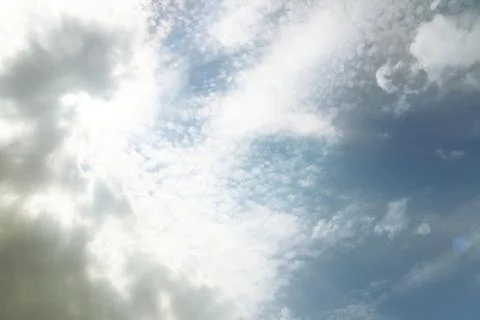 The sun shines through the clouds in the blue sky. Natural background for lat Stock Photos