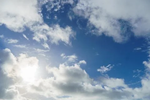 The sun shines through the clouds in a blue sky landscape Stock Photos