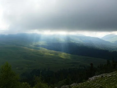 The sun shines through the clouds in the mountains in the valley Stock Photos