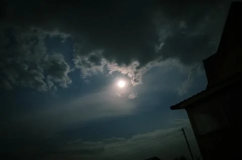 The sun shines through the clouds in the night sky. The moon shines through the  Fotos Stock