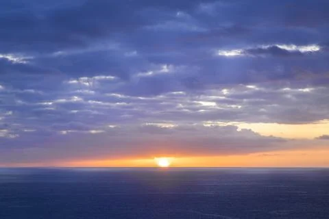 The sun shines through the clouds over the ocean. Beautiful, colorful sunset. Stock Photos