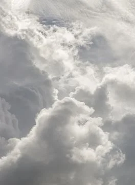 The sun shines through the clouds in the sky.  The shape of the clouds evokes Stock Photos