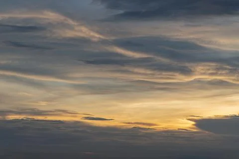 The sun shines through the clouds in the sky.  The shape of the clouds evokes Stock Photos
