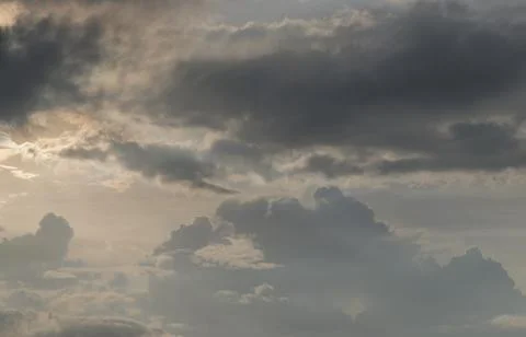 The sun shines through the clouds in the sunset sky with dramatic light. Stock Photos