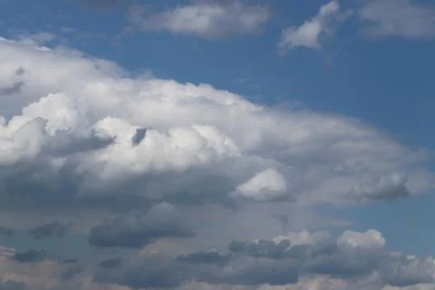 The sun shines through the cumulus clouds in the blue sky. Background and tex Stock Photos