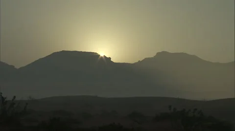 The Sun shines through mountain ranges in a desert. Stock Footage 46870326