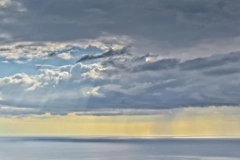 Sun shines through rain clouds over Tasman sea horizon Foto stock