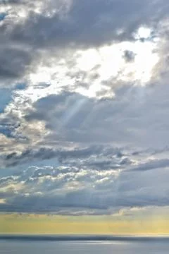 Sun shines through rain clouds over Tasman sea horizon Stock Photos