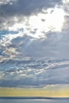 Sun shines through rain clouds over Tasman sea horizon Stock Photos