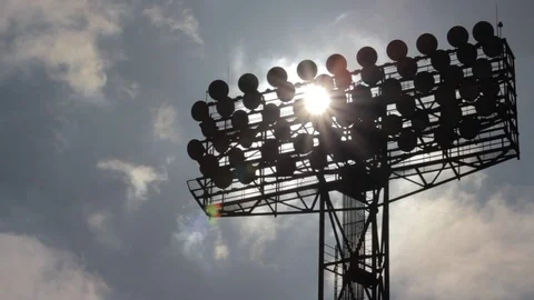Sun shines through the stadium lights against the background of moving clouds. Stock Footage