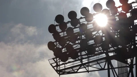 Sun shines through the stadium lights against the background of moving clouds. Stock Footage 73705146