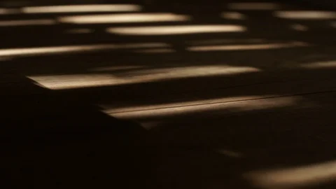 Sun shines through window shutters - creates moving shadows on floor 스톡 동영상 107656464