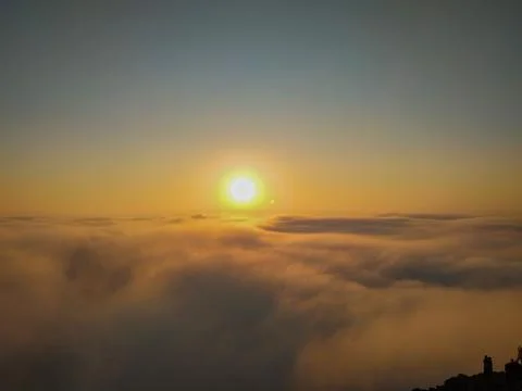 The sun shining above the clouds on a cliff Photos