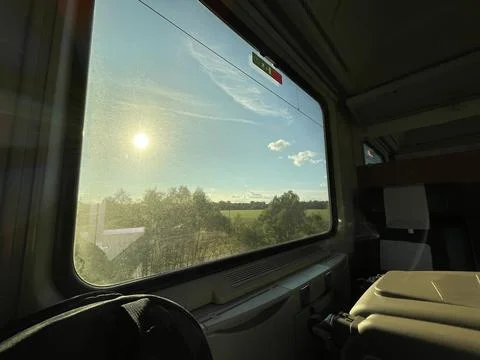 Sun shining above green fields, landscape view from window of a train Stock Photos