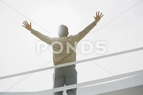 Sun shining behind businessman with arms raised Stock Photos