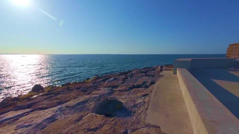 Sun shining brightly over sea horizon on rocky coast Stock Footage 340450461