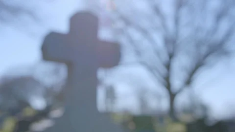 Sun shining down on cross headstone at Greenwood Cemetery, rack focus, 4k60p Stock Footage 128782301