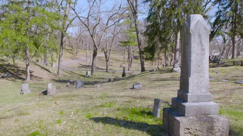 Sun shining down on headstones and through trees at Greenwood Cemetery, 4k60p Stock Footage 128784333