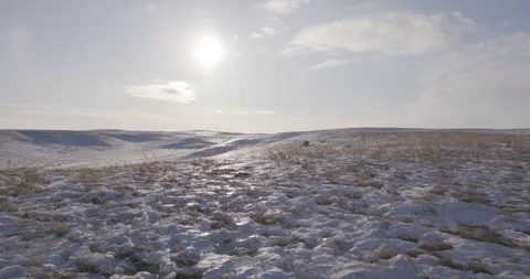 Sun shining on grassland covered in patchy snow Stock Footage 332379778