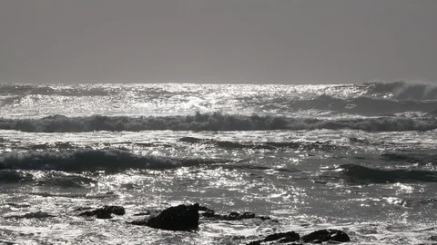 Sun shining on ocean surface at dusk as powerful white waves throw up spray Stock Footage 103642519