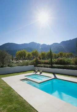 Sun shining over idyllic, tranquil lap pool with mountain view Fotos de archivo