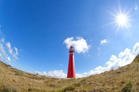 Sun shining over red lighthouse Stock Photos
