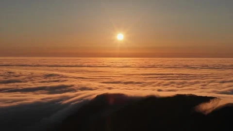 Sun shining over a sea of clouds during golden hour Stock Footage 317102504