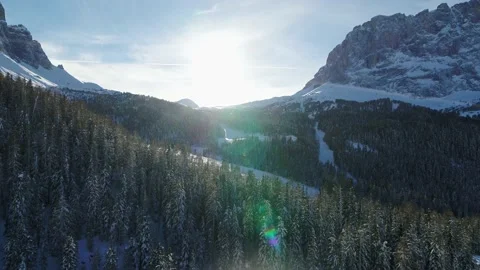 Sun shining over Snow covered Forest and mountains in the Alps. Aerial view Stock Footage 150075150