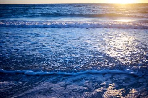 Sun shining over waves breaking on beach Foto stock