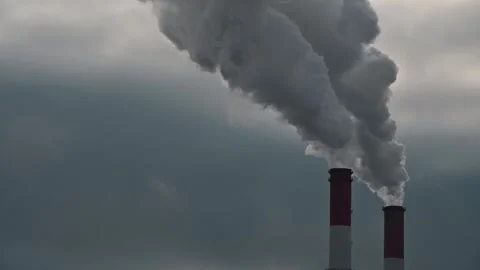 Sun shining through clouds of industrial smoke from power plant smokestacks i Stock Footage 257334967