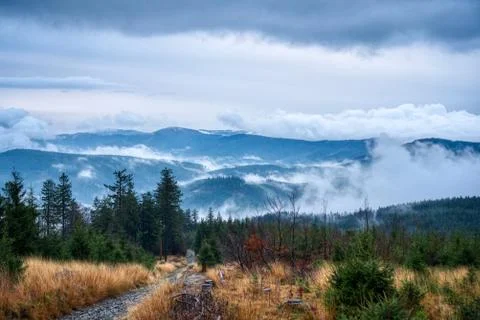 Sun shining through the clouds in the mountains with fog on the hill Stock Photos