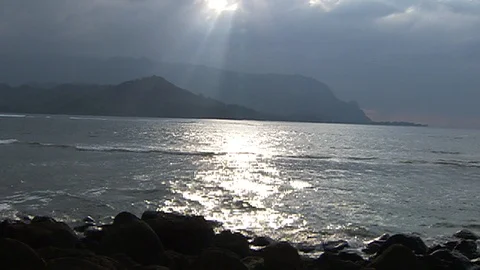 Sun shining through clouds. Ocean waves mountain and rocks Stock Footage 102527910