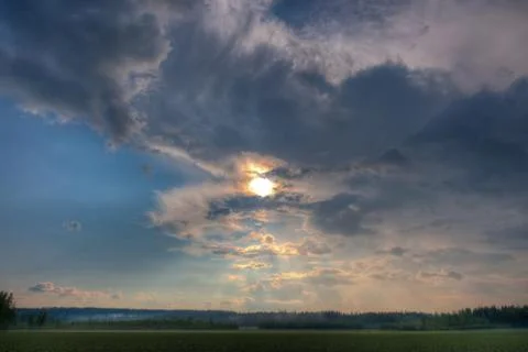 Sun shining through clouds over a wheat field Stock Photos