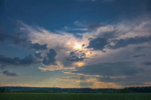 Sun shining through clouds over a wheat field Stock Photos