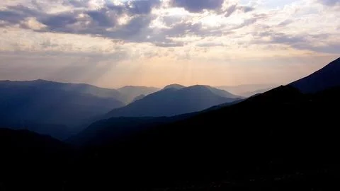 The sun is shining through the clouds over the mountains Stock Photos