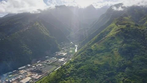 Sun shining through clouds over lush valley in tropical Tahiti island Stock Photos
