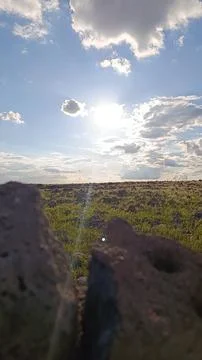 Sun Shining Through Clouds Over Rocky Grass Field Landscape Stock Photos