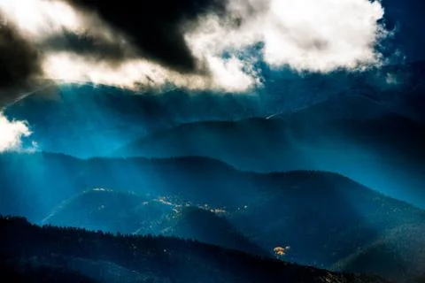 Sun shining through the dark clouds over the mountains Sand Dunes National Pr Stock Photos
