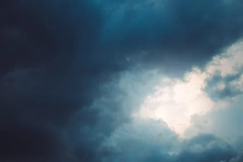 Sun shining through dark clouds Stock Photos